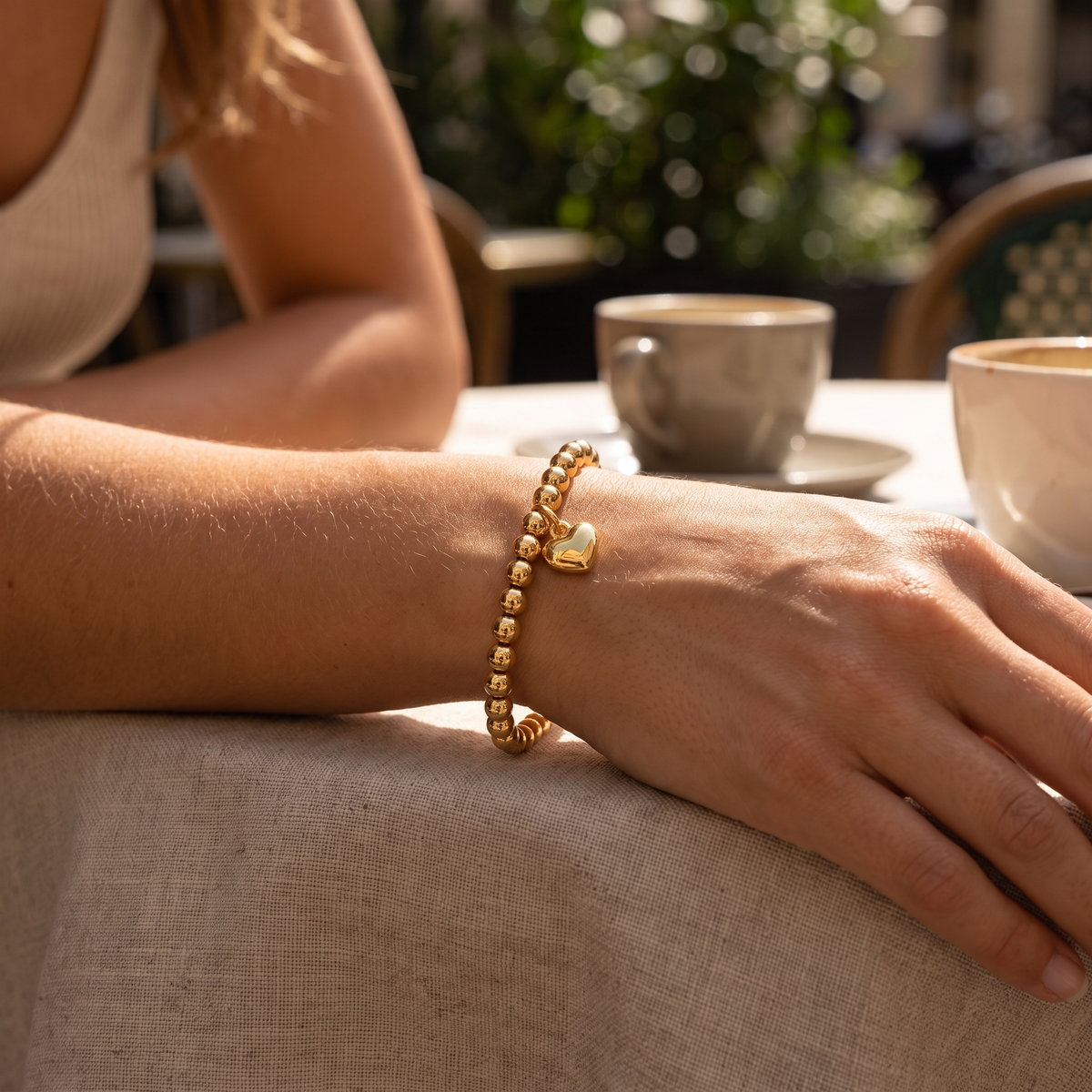 Gold beaded charm bracelet styled on wrist